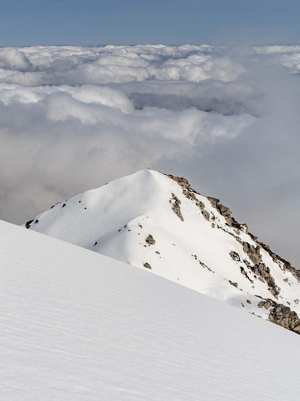 At the peak of a snow mountain in the midst of clouds At the peak of a snow mountain in the midst of clouds