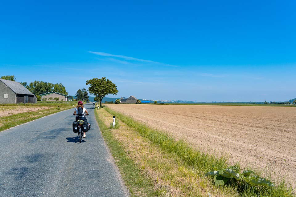 Kaitlan riding past farmland fields on a paved road on the KTM Touring E-Bike Kaitlan riding past farmland fields on a paved road on the KTM Touring E-Bike