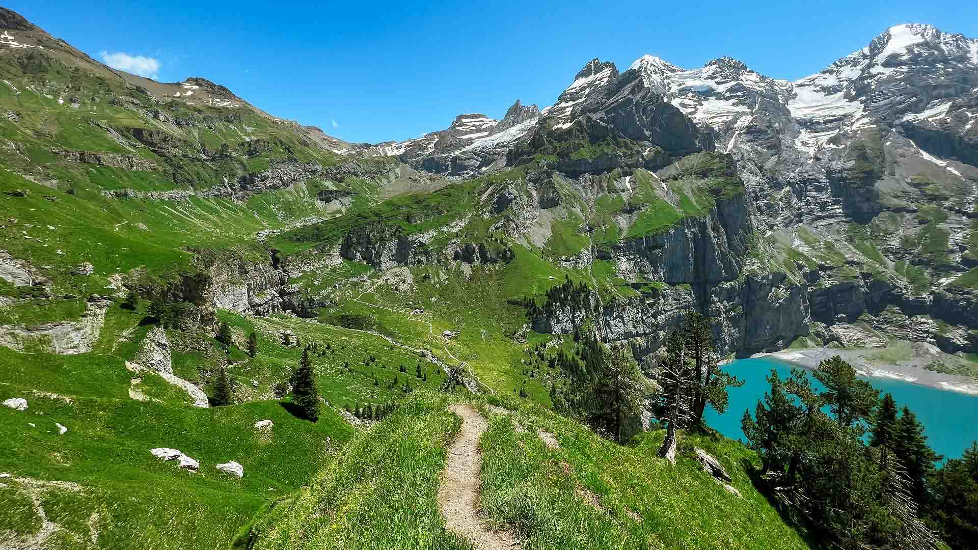 View of the hiking trail contrasing with Lake Oeschinen below View of the hiking trail contrasing with Lake Oeschinen below